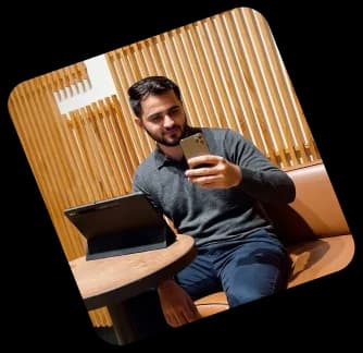 Man checking his phone beside a laptop